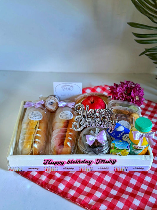 Breakfast with Sandwiches in a Tray – a beautifully arranged wooden tray with cheddar cheese and smoked turkey sandwiches, toast, a muffin cake, fresh fruit, juice, tea, Hero jam, butter, chocolates, and nuts. Decorated with a birthday topper, flowers, and a celebratory balloon.