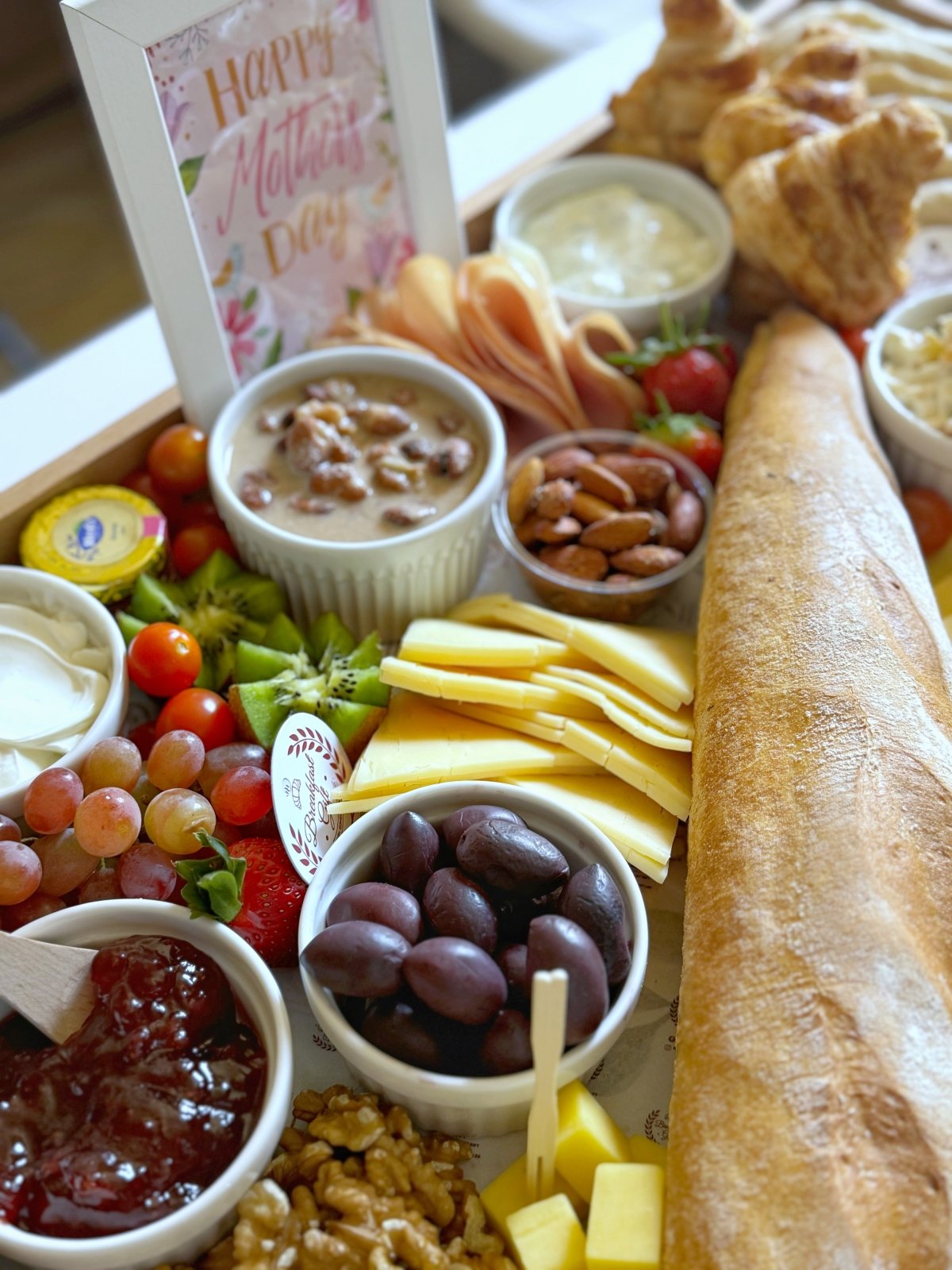 A beautifully arranged Family Suhoor Mother’s Day Gift Tray with gourmet cheeses, fresh fruits, artisan breads, and cold cuts in a wooden serving tray.