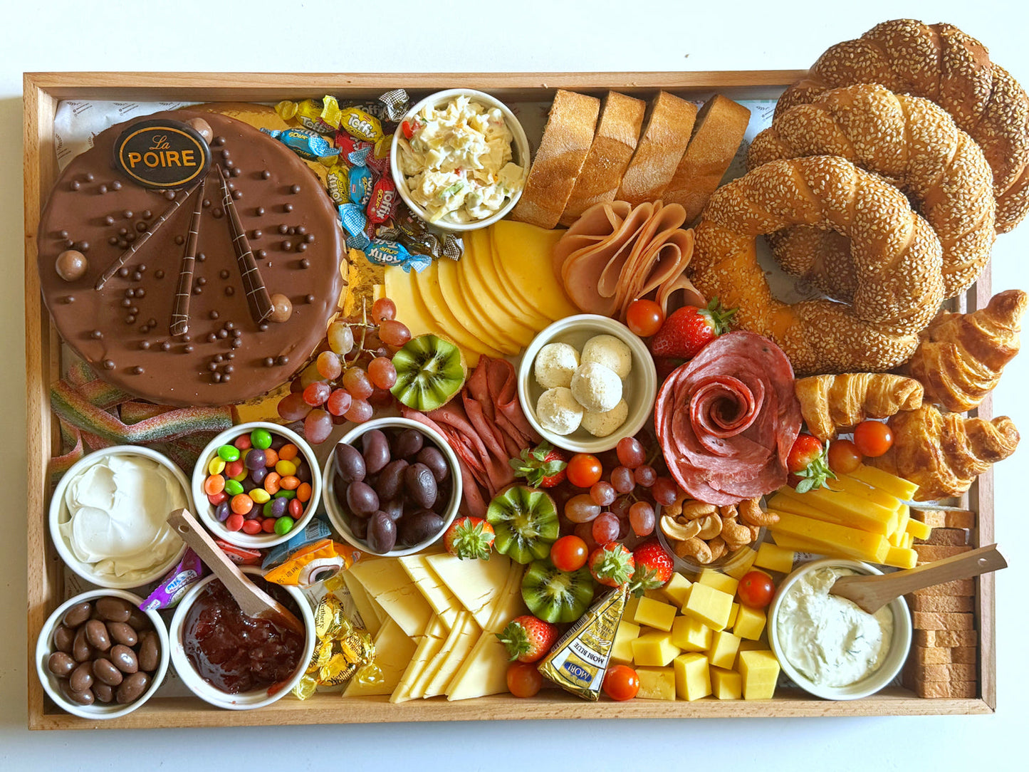Top view of The Celebration Tray showcasing all components including cake, deli meats, dips, candies, and artisan bread.