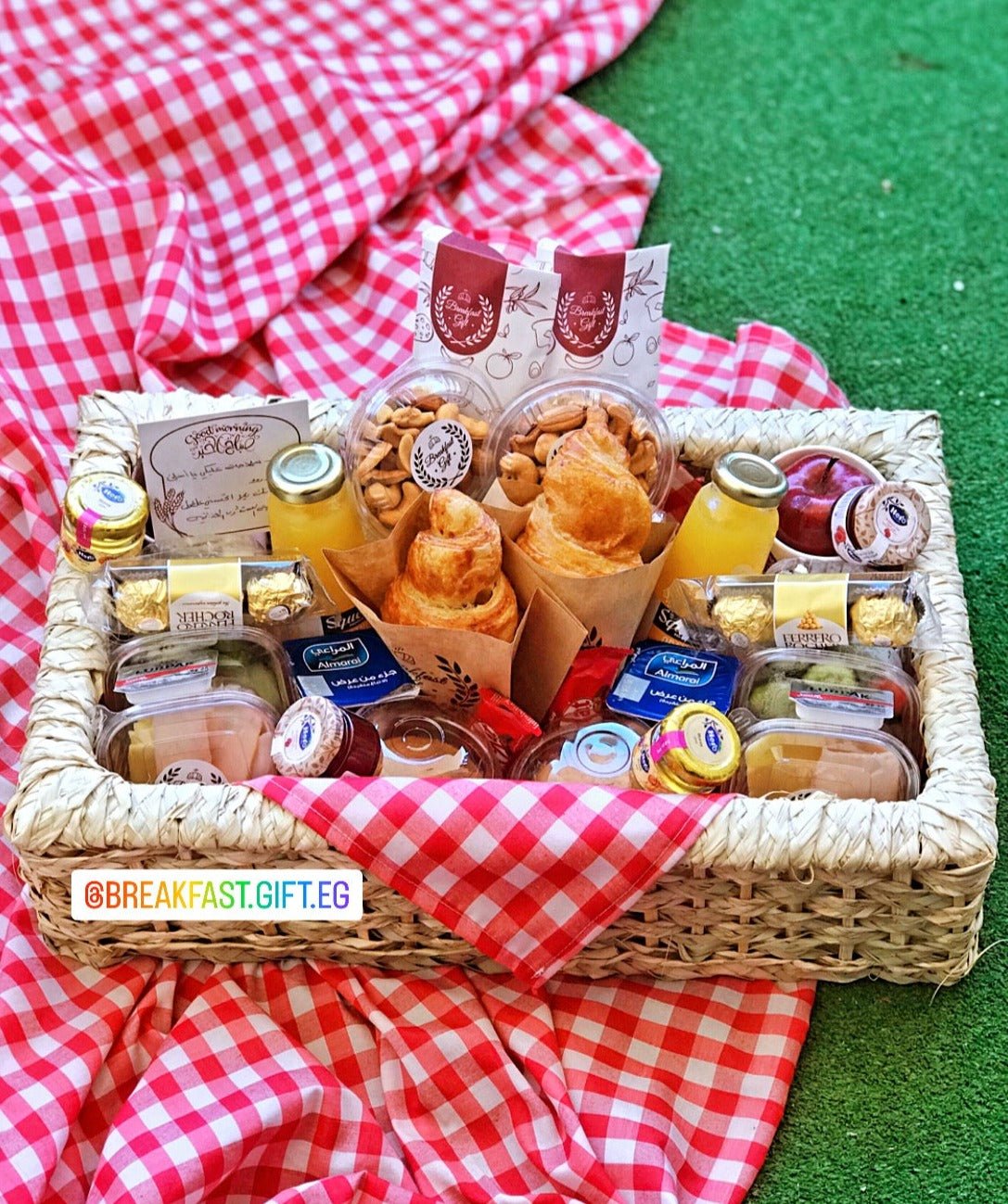 Basic Breakfast Basket for Two – a beautifully arranged wicker tray featuring flaky croissants, toast, muffins, fresh fruits, deli meats, cheeses, honey, jam, butter, chocolates, nuts, and refreshing natural juices. Includes a small mat for a cozy breakfast experience, making it a perfect gift for couples, friends, or family members.