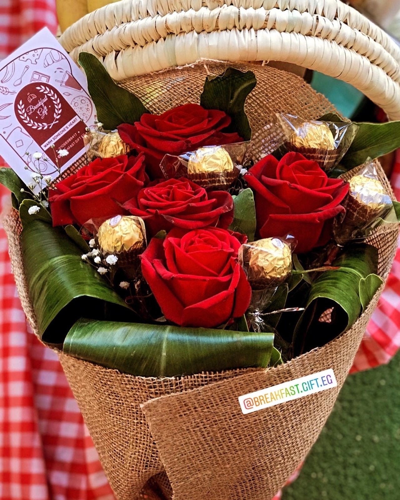 Flowers with Chocolate Delight bouquet featuring five fresh red roses, Ferrero Rocher-style chocolates, elegant burlap wrapping, green leaves, and decorative white baby's breath flowers. A sophisticated floral and chocolate arrangement, perfect for special occasions and heartfelt gestures.
