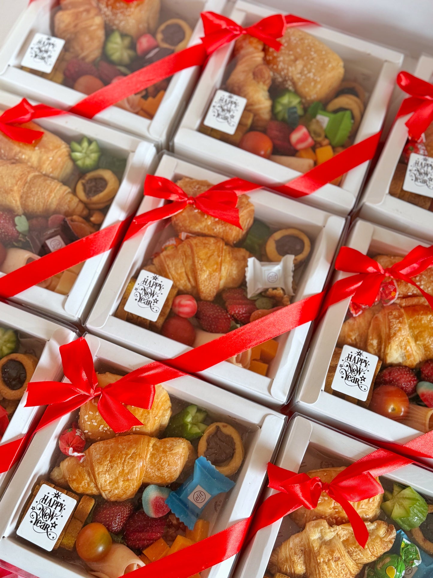 A close-up of the Corporate Gift Box displaying a delicious combination of savory and sweet treats, including a croissant, turkey slices, cheddar cheese, chocolate, and fresh fruits, making it an ideal business gifting option.