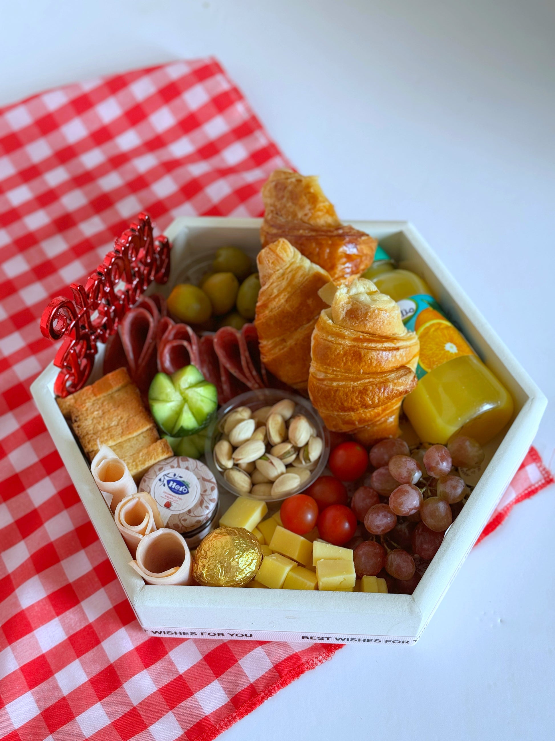 A beautifully wrapped Birthday Breakfast Hexagonal Platter featuring a vibrant ‘Happy Birthday’ balloon, elegantly packaged with a luxurious selection of croissants, cheeses, fruits, and premium treats for a delightful morning celebration.