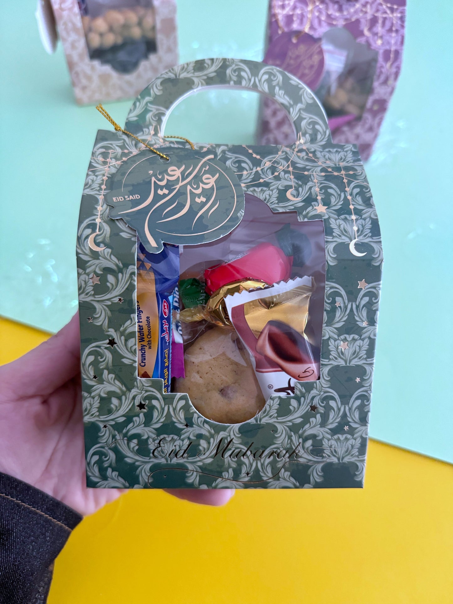 Eid Elegance Box – Golden Patterns – Close-up of box held in hand showing sweets packed inside through window