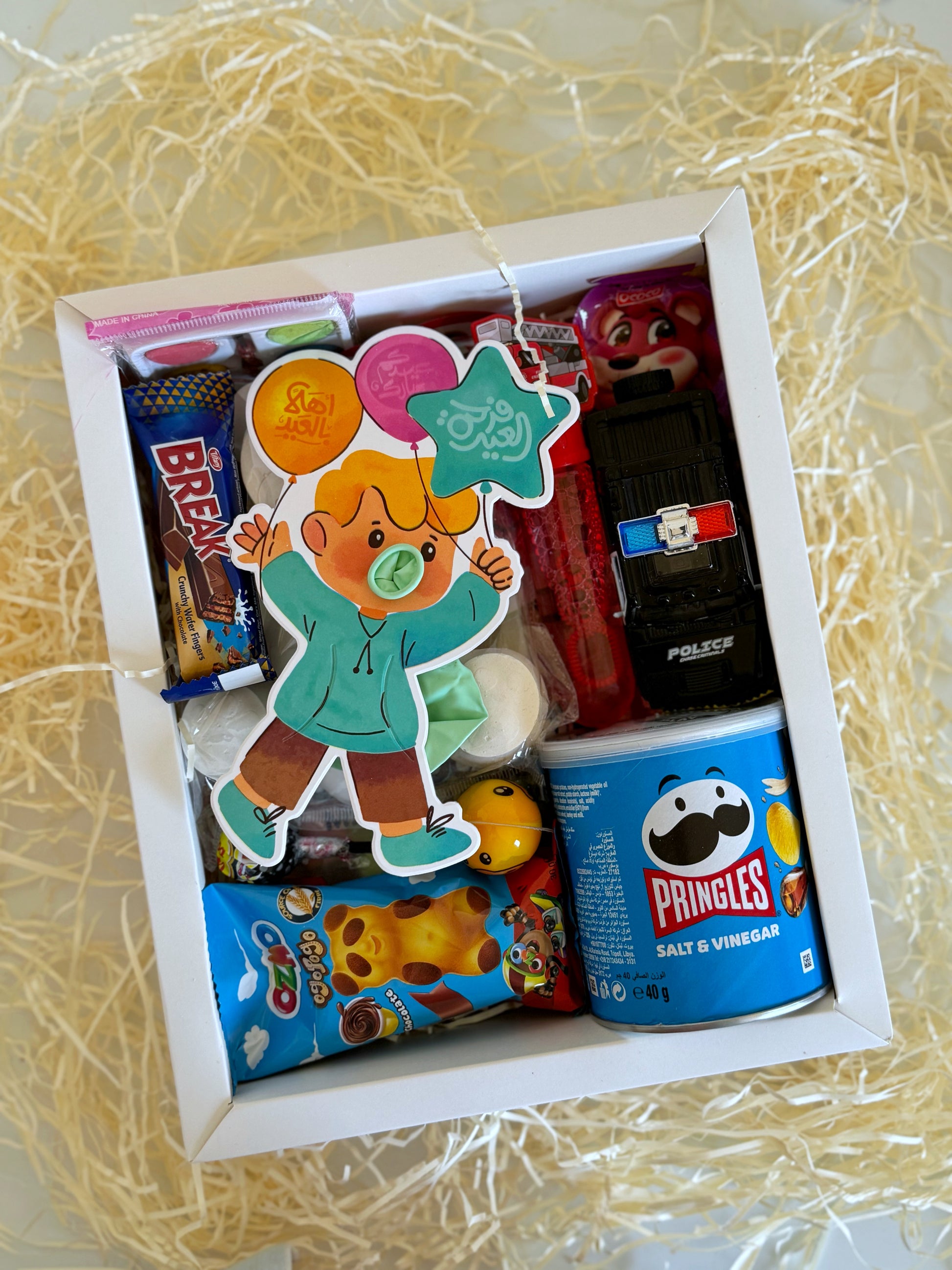 The Eid Festive Surprise - Boy gift box, showing chocolates, a toy car, marshmallows, a coloring activity, and a variety of sweets.
