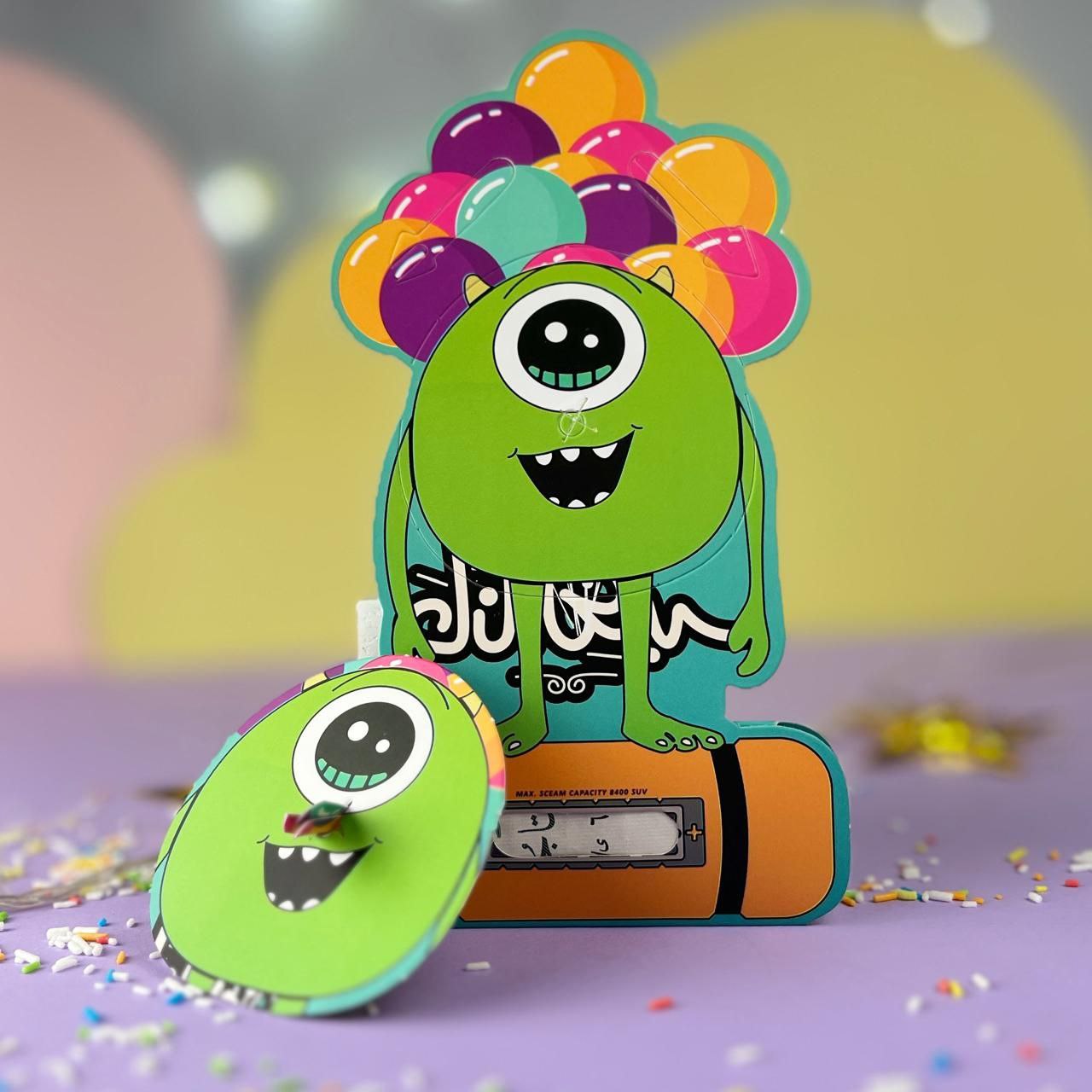 A green one-eyed monster-themed Eid money card that transforms into a toy, featuring a fun interactive design.