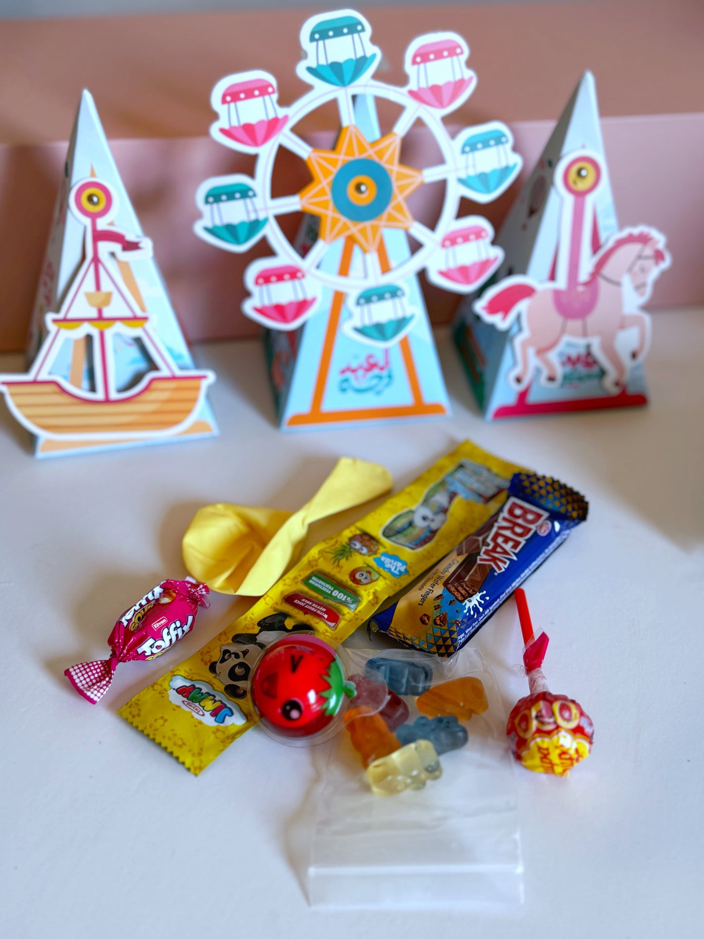 The Movable Eid Pyramid Set opened to reveal a selection of sweets, including a chocolate bar, gummy candy, lollipop, toffee, a balloon, and a small surprise toy.