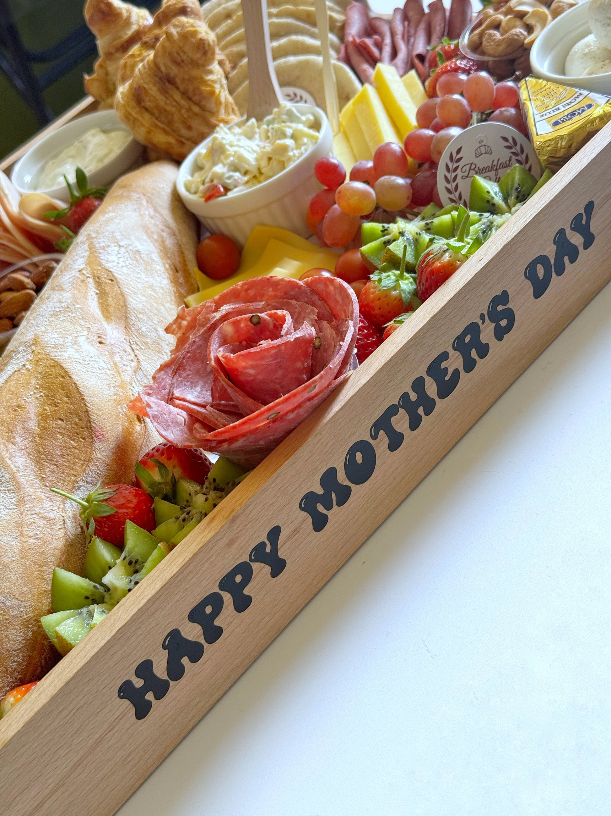 A luxurious Family Suhoor Mother’s Day tray featuring gourmet cheeses, baguette, croissants, and a Happy Mother’s Day frame.