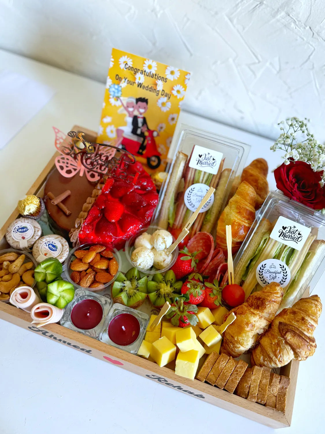 Overhead view of the Just Married Breakfast tray showing croissants, cakes, cold cuts, cheeses, nuts, and a wedding greeting card.