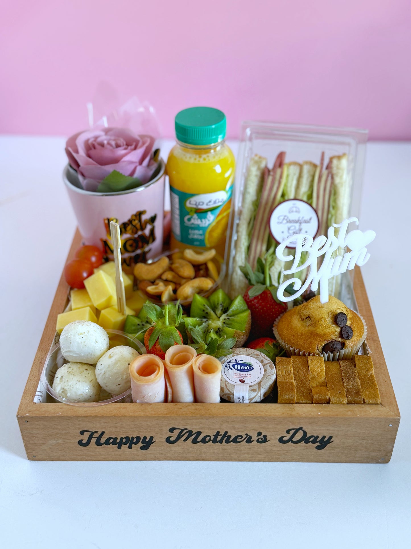 A beautifully arranged Mother’s Day Breakfast Tray featuring a club sandwich, fresh fruits, a “Best Mom Ever” mug, and a chocolate chip muffin in an elegant wooden tray.