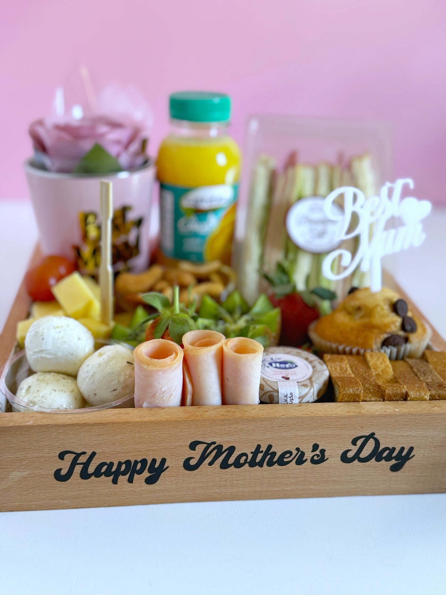 A close-up of the Mother’s Day Breakfast Tray, showcasing fresh kiwi, cheddar cheese cubes, turkey slices, nuts, and a refreshing bottle of juice.