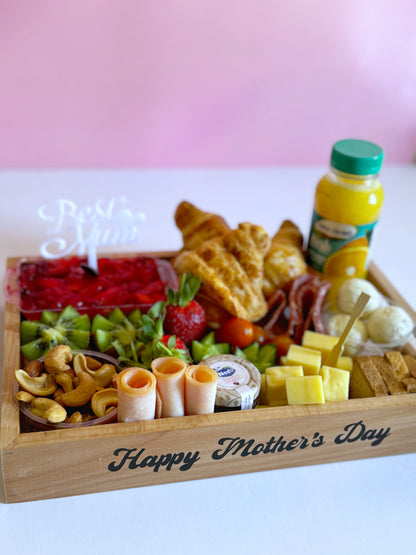 A beautifully arranged Mother's Day breakfast tray featuring kunafa with strawberries, croissants, fresh juice, premium cheeses, cold cuts, and fresh fruits.