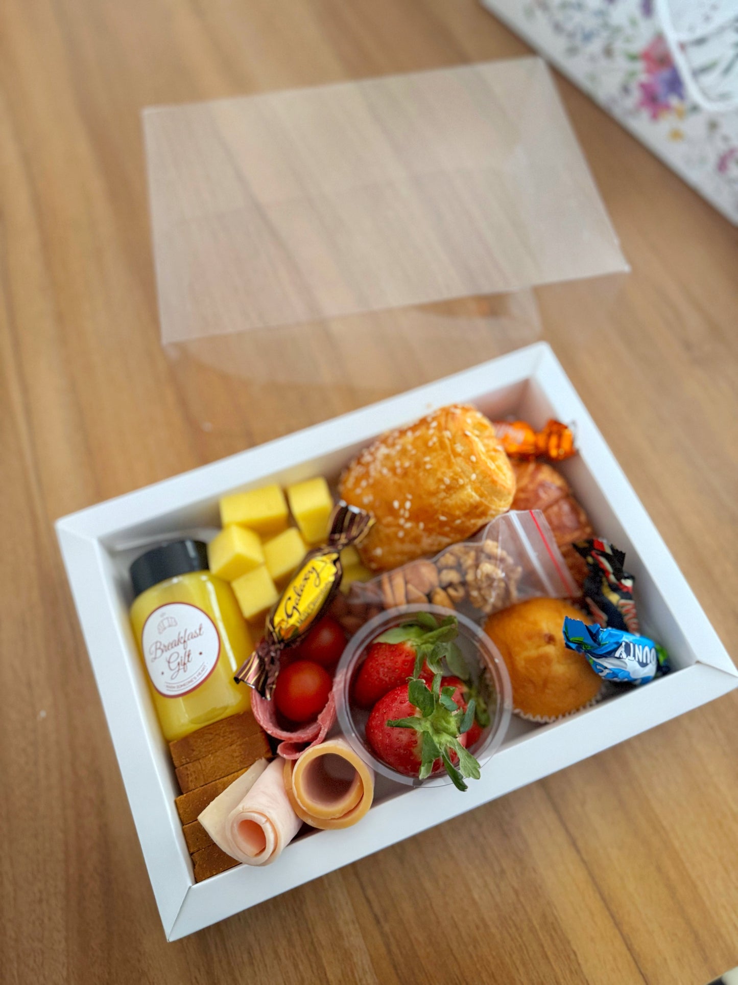 Premium Box – Single open box with clear lid propped, showing full contents including juice bottle and seasonal fruit