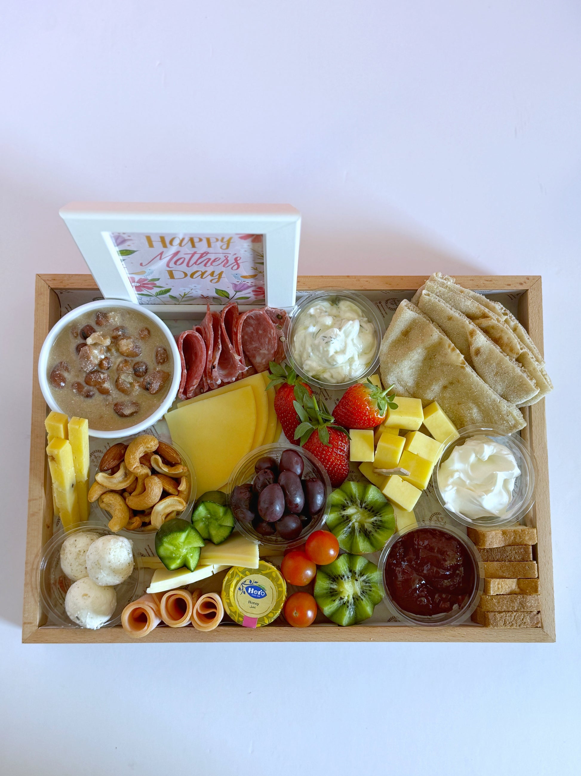 Top-down view of the Sohour Mother’s Day tray showcasing an elegant selection of cheeses, fresh fruits, toasted bread, and a decorative Mother's Day frame.