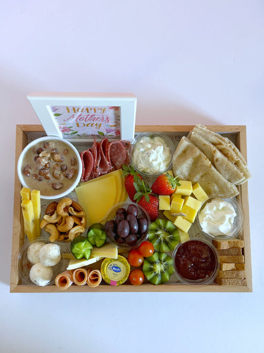 Top-down view of the Sohour Mother’s Day tray showcasing an elegant selection of cheeses, fresh fruits, toasted bread, and a decorative Mother's Day frame.