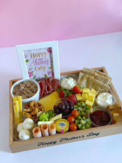 A beautifully arranged Sohour Mother’s Day wooden tray featuring a variety of cheeses, cold cuts, nuts, fresh fruits, toasted bread, and a framed "Happy Mother’s Day" sign.