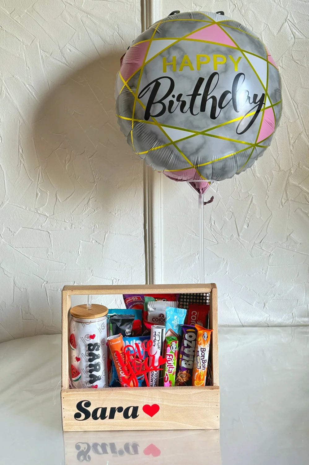 The full Sugar Rush Surprise gift display with the crate and contents, topped with a large round balloon that reads “Happy Birthday.”