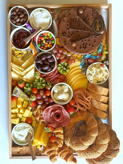 Top view of The Celebration Tray showcasing all components including cake, deli meats, dips, candies, and artisan bread.
