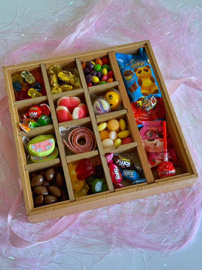  close-up of the wooden gift box filled with Skittles, chocolate-coated peanuts, gummy bears, and an Ozmo cake, decorated for Eid celebrations.